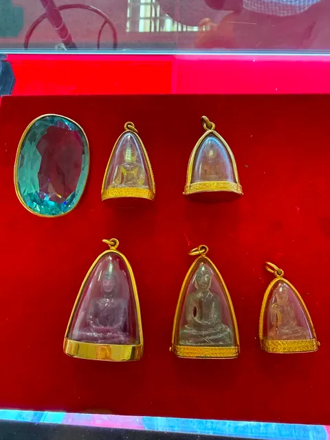 พระเลี่ยมกรอบทองและพลอยเรือนทองบนถาดกำมะหยี่