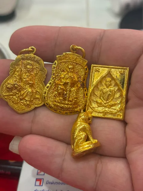 พระทองคำและเหรียญทองคำหลายองค์บนมือ